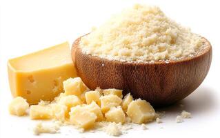 Freshly grated cheese in wooden bowl. A wooden bowl holds freshly grated cheese alongside chunks of cheese, highlighting its texture and color. photo