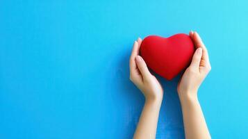 Heartfelt Affection Hands Gently Holding a Red Heart on a Sky Blue Background Symbolizing Love and Care photo