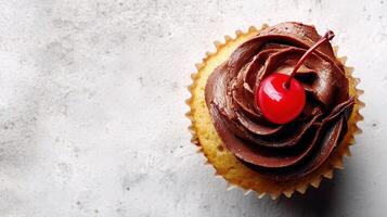 A cupcake with chocolate frosting and a cherry on top photo