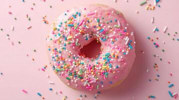A pink donut with sprinkles on a pink background photo