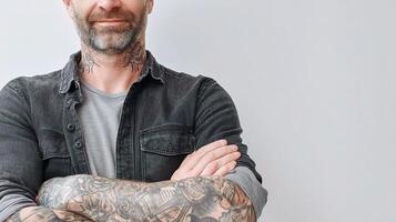 A man with tattoos standing with his arms crossed photo