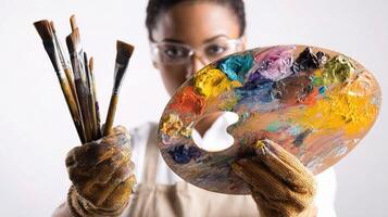 A woman holding a palette of paint brushes and a paint brush photo