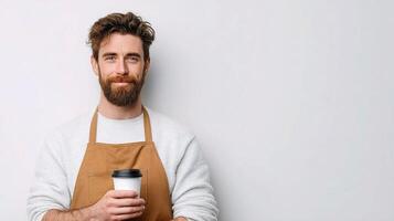 A bearded man with an apron holding a coffee cup photo