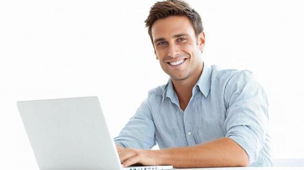 A smiling man is sitting at a table with a laptop photo