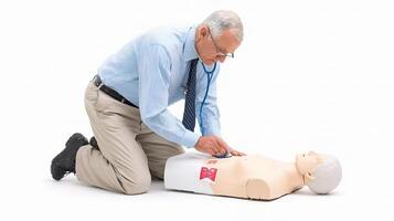 A man is kneeling down to check on a cpr dummy photo