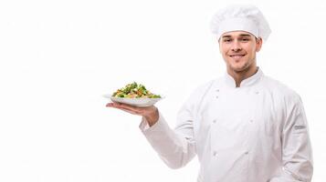 A male chef holding a plate with a salad photo