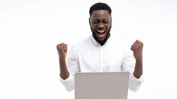 A man is excited and holding his fist up while using a laptop photo