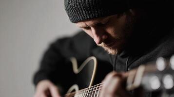 A man in a beanie playing an acoustic guitar photo