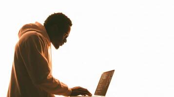 A silhouette of a man in a hoodie using a laptop photo