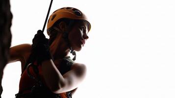 A woman in a helmet and safety gear is climbing a rock wall photo