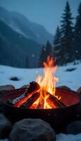 A fire pit is shown in the snow with a mountain in the background photo