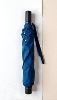 A blue umbrella with a black handle on a white surface photo