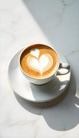 A cappuccino with a heart design on top of a white table photo