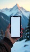 A person holding up a white iphone with a mountain in the background photo
