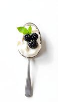 Yogurt with blackberries on a spoon isolated on white background photo