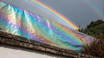 A rainbow is seen over a building with a tarp over it photo