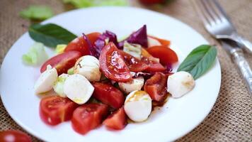 Salad with mozzarella and tomatoes on a wooden table video