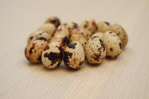 a cluster of quail eggs arranged neatly on a light wooden surface photo