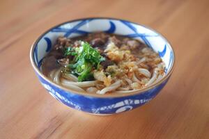 a bowl of Japanese-style noodle soup, likely udon, served in a beautifully patterned blue and white bowl photo