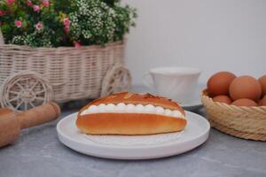 Cream-Filled Almond Pastry on a Plate with Eggs and Flowers photo