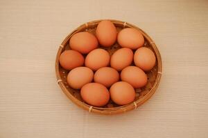 A basket filled with fresh brown eggs on a wooden table photo
