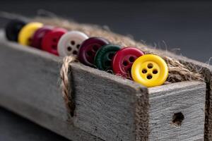 Colorful buttons arranged in a wooden box for sewing and crafting activities in natural lighting photo