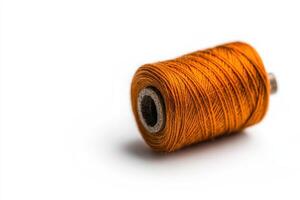 Bright orange sewing thread spool placed on white background for crafting and sewing projects photo