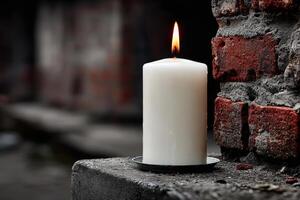 Candle placed against a weathered brick wall in a dimly lit area during evening hours photo