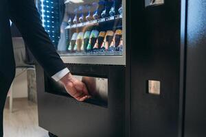 A man in a suit is reaching into a vending machine photo