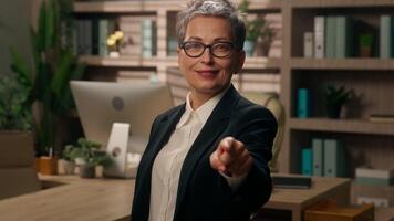 Caucasian smiling old business woman pointing hey you looking at camera showing thumb up like in office mature businesswoman female support success work good result approve choosing with index finger video