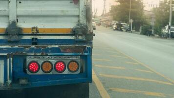 Beside of truck car open brake signal. Stop on the empty road. Front of the car is an intersection with traffic lights. With city side of opposit road and trees. photo
