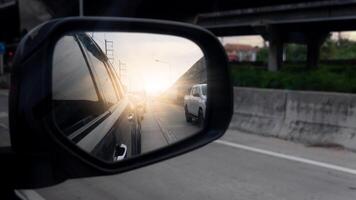 Side of mirror view on concrete road. Car line up from the rear. Concrete road with overpass on the side. Sunlight shines through at night. photo