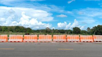 Aspahlt road with barrier guard lens. Background is a grassland and cows, which is an agricultural area and some forest. Under a blue sky. photo