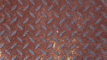 Close up of a rusty metal Lid plate. Raised textured pattern of Lid provides a non slip surface. Overall color is reddish brown due to significant rust formation typical of aged met. photo