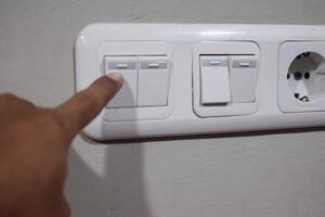 Fingers are turning offlight switch in the house, concept for energy saving reduce global warming photo