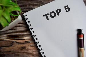 Concept of TOP 5 on book isolated on Wooden Table. photo