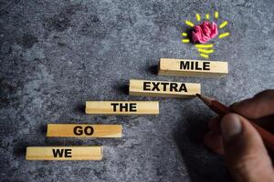 Concept of We go the extra mile Symbol. Wooden blocks stacking as step stair We go the extra mile photo