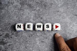 male hand presses the play button with news on dice or wooden cubes photo