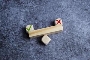 Tick mark outweight cross mark on and imbalanced seesaw. Concept of positive evaluation in decision making. photo