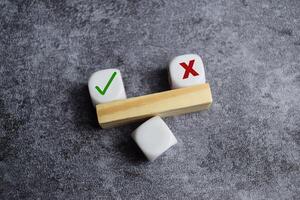 Tick mark outweight cross mark on and imbalanced seesaw. Concept of positive evaluation in decision making.. photo