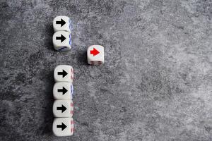 Wooden blocks or dice with arrows with one moving forward and standing out from the crowd. Concept of competitive advantage business startup photo