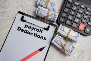 Concept of Payroll Deductions write on paperwork isolated on Wooden Table. photo