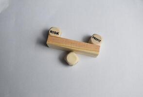 Words profit and risk are written on a seesaw made of wooden blocks on the white background. concept of profit and risk analysis in business or risk management photo