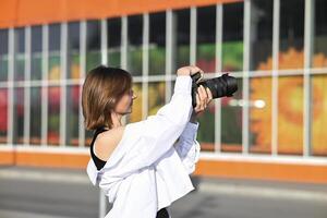 She is standing in profile, facing to the right, and taking a photograph. photo