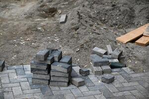 Low angle view of male hands measuring and leveling sand and cement tiles for precise pavement of the outside patio or sidewalk. Construction industry and renovation. photo