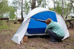 A woman sets up a tent in the forest. Activity people. photo