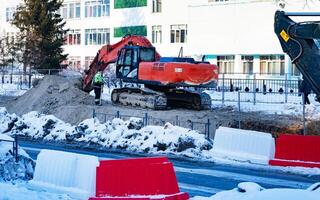 Excavator during earthmoving on blue sky background. Construction machinery and earth-moving heavy equipment for excavation, loading, lifting and hauling of cargo on job sites photo