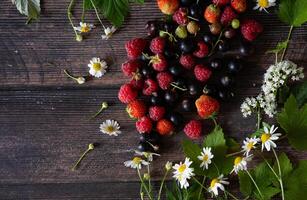 Fresh berries. Red currants and raspberries in bowls on a large wooden board with mint leaves, strawberries and pomegranate seeds. Background image, top view, vertical photo