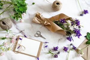 The image displays a flat lay composition of floral arranging supplies on a marble surface. photo