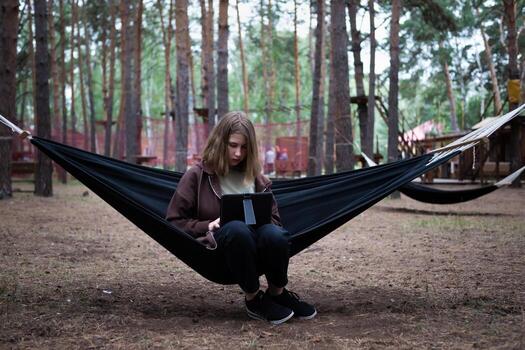 A girl in a hammock is working on a computer photo